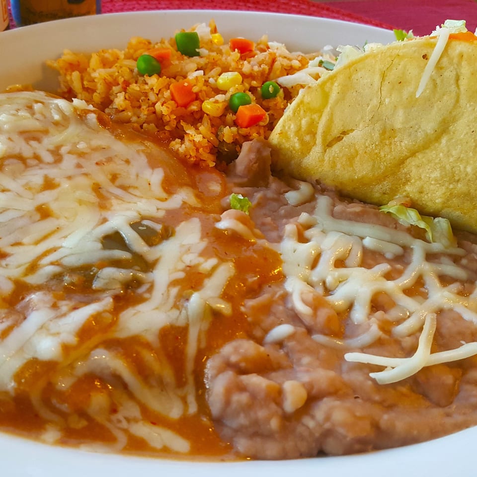 A Mexican combo plate with cheesy enchiladas, refried beans, rice with vegetables, and a crispy taco.