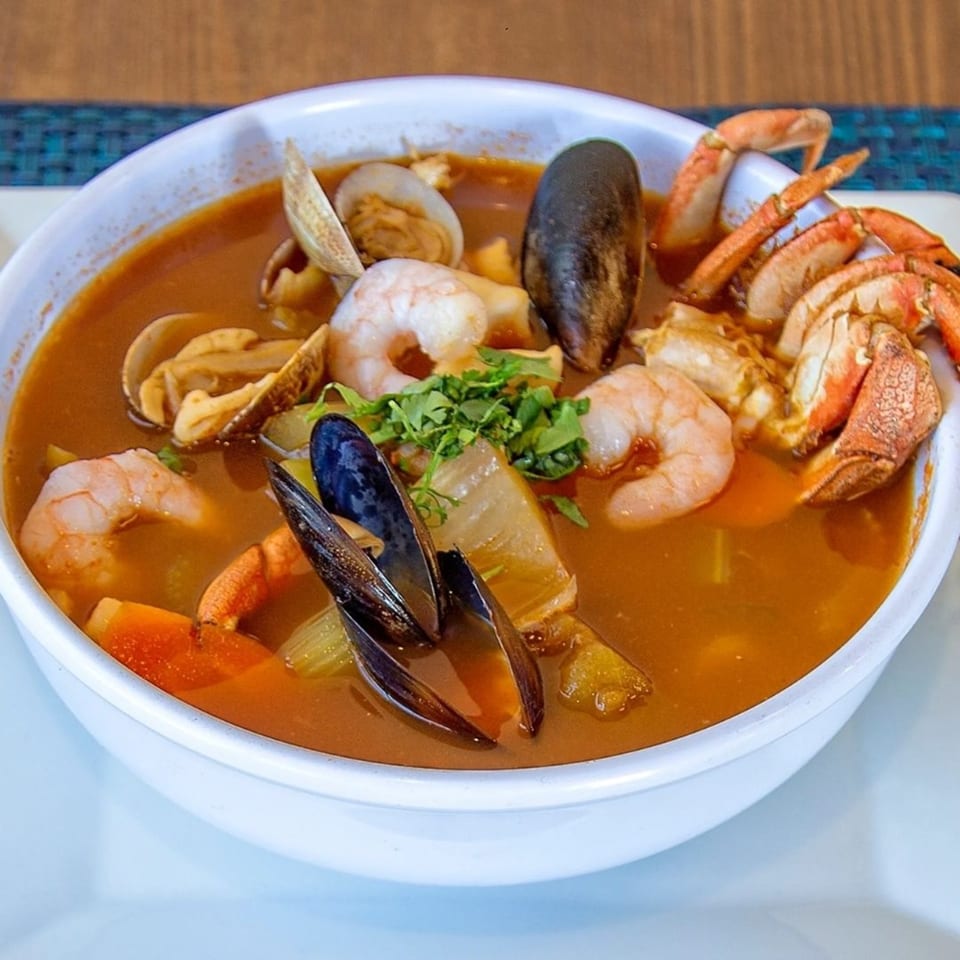 A large bowl of Ruben's Mariscos seafood soup with shrimp, mussels, clams, and crab legs.