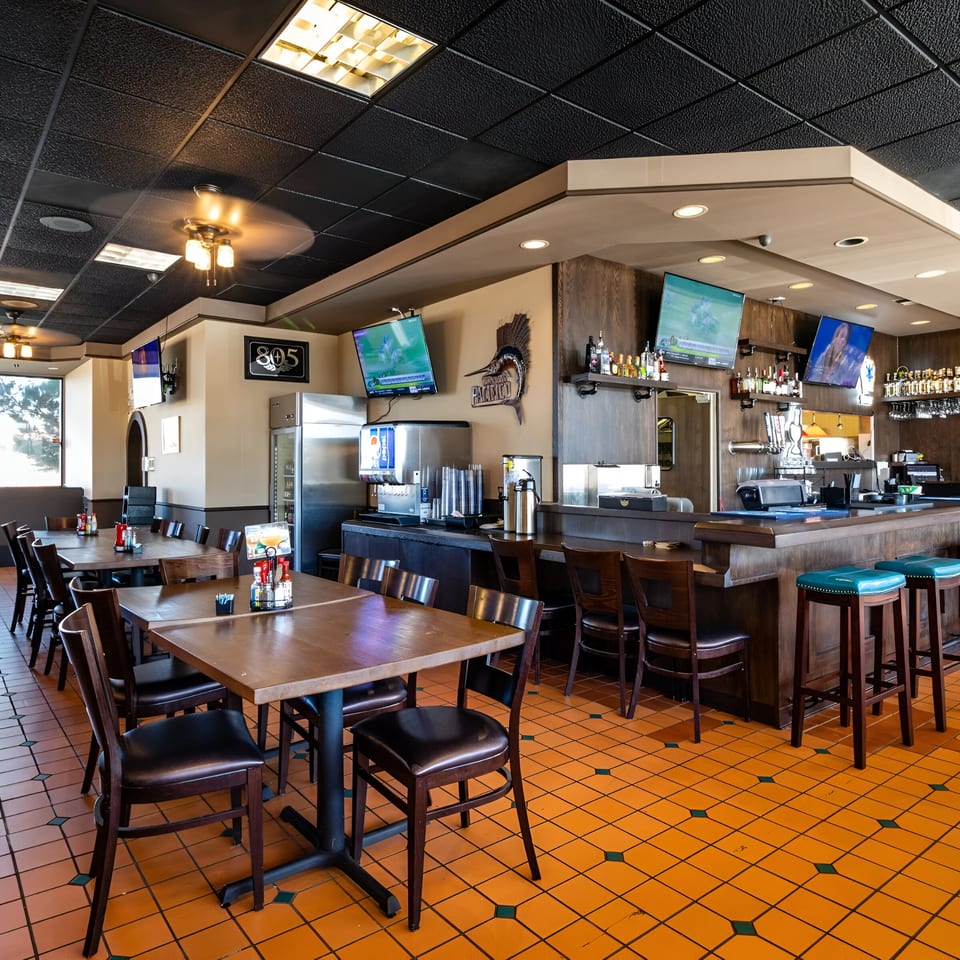 Interior of Ruben's Mariscos and Mexican Grill, showing dining tables, a bar, and TVs.